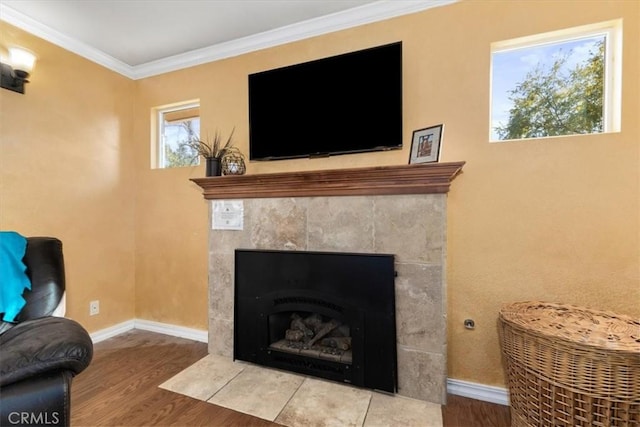 room details with crown molding, wood-type flooring, and a tiled fireplace