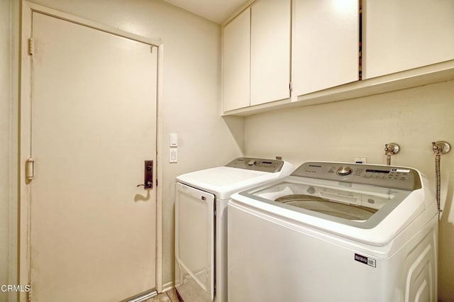 clothes washing area featuring cabinets and washing machine and clothes dryer