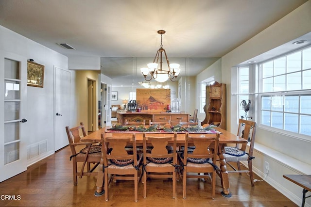 dining room with dark wood-type flooring and a notable chandelier