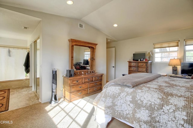 bedroom with vaulted ceiling, light colored carpet, and a closet