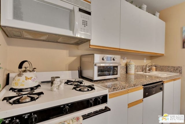 kitchen featuring white cabinetry, light stone countertops, sink, and white appliances