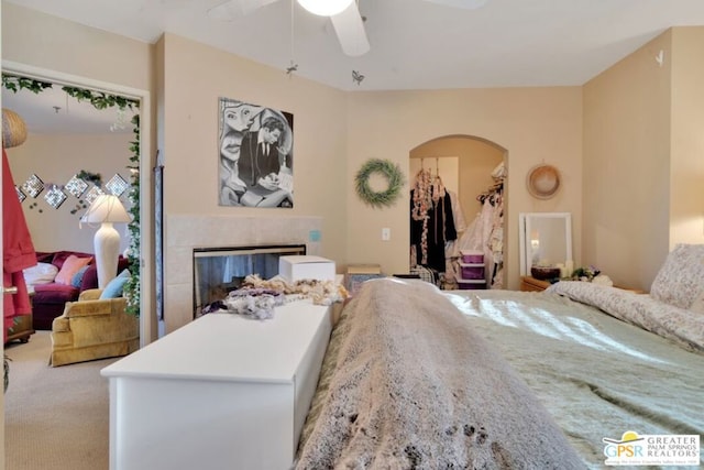 carpeted bedroom featuring a fireplace and ceiling fan