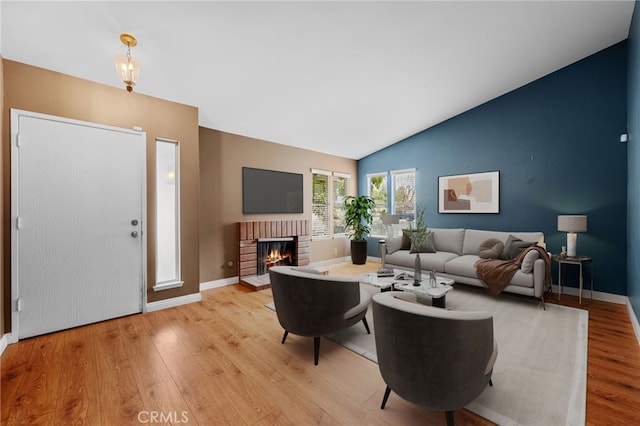 living room with lofted ceiling, a fireplace, and light hardwood / wood-style flooring