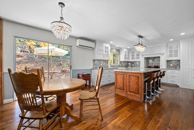 dining space featuring an AC wall unit, a chandelier, a wealth of natural light, and dark hardwood / wood-style flooring