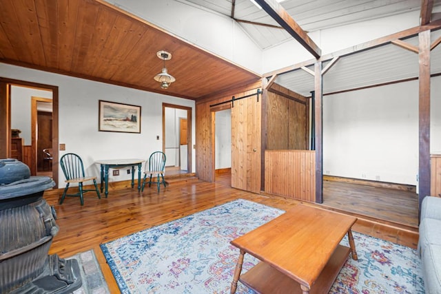 living area featuring crown molding, wood-type flooring, a barn door, and wood walls