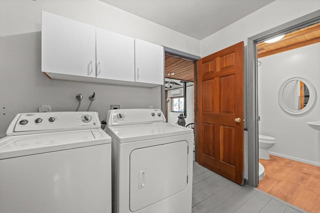 clothes washing area featuring cabinets and washer and clothes dryer