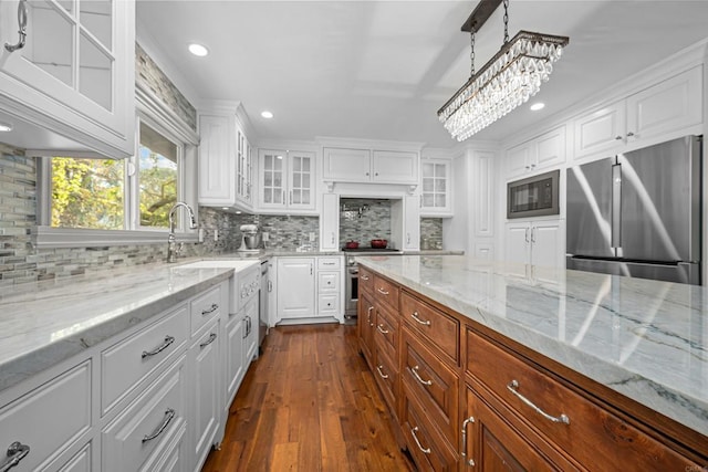 kitchen featuring white cabinetry, hanging light fixtures, stainless steel appliances, light stone counters, and decorative backsplash