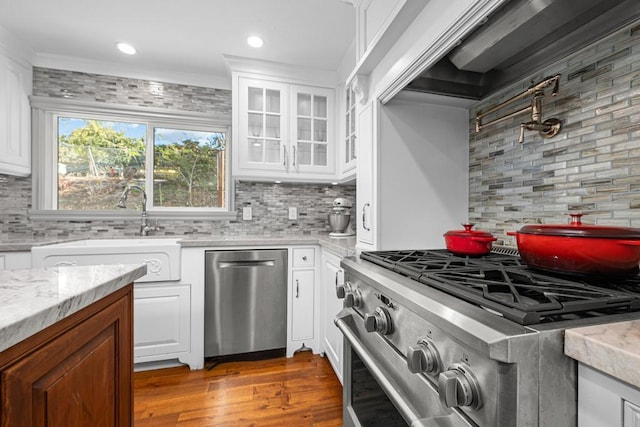 kitchen with white cabinetry, wood-type flooring, sink, backsplash, and stainless steel appliances