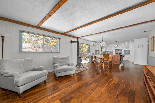 living room featuring beamed ceiling, dark hardwood / wood-style flooring, a textured ceiling, and an AC wall unit