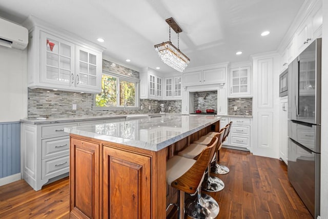 kitchen featuring white cabinetry, a kitchen island, stainless steel refrigerator, and decorative light fixtures