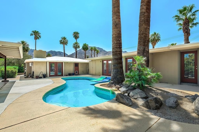 view of pool with french doors, a mountain view, and a patio