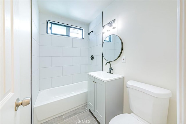 full bathroom featuring tiled shower / bath, vanity, and toilet