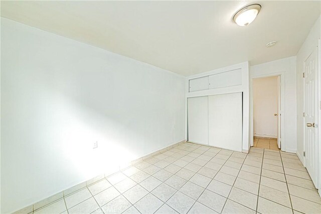 unfurnished bedroom featuring light tile patterned floors and a closet