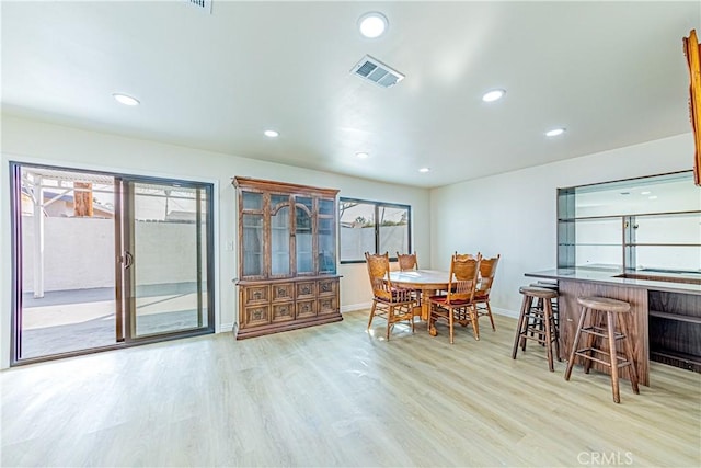 dining area with indoor bar and light wood-type flooring