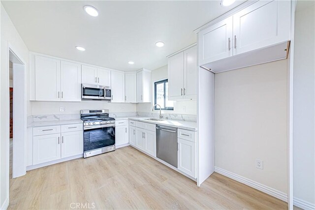 kitchen with white cabinetry, appliances with stainless steel finishes, sink, and light wood-type flooring