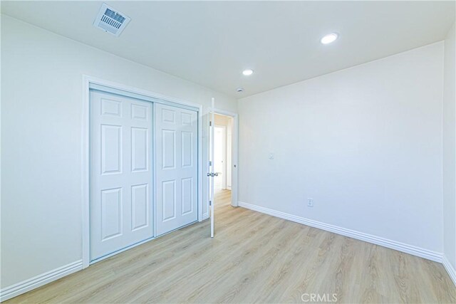unfurnished bedroom with a closet and light wood-type flooring