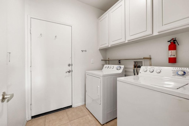 laundry room featuring cabinets, light tile patterned floors, and washing machine and clothes dryer