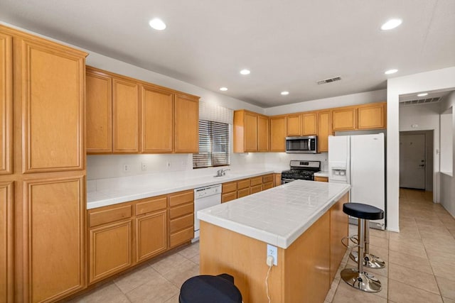 kitchen featuring appliances with stainless steel finishes, tile counters, a kitchen island, and light tile patterned floors