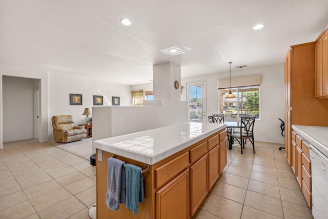 kitchen featuring dishwasher, tile counters, light tile patterned floors, and decorative light fixtures