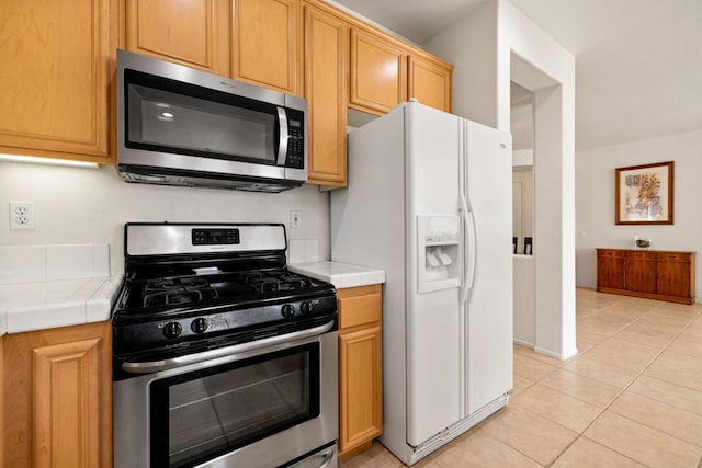 kitchen with light tile patterned floors, tile counters, and appliances with stainless steel finishes