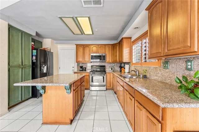 kitchen featuring a kitchen island, sink, decorative backsplash, light tile patterned floors, and stainless steel appliances