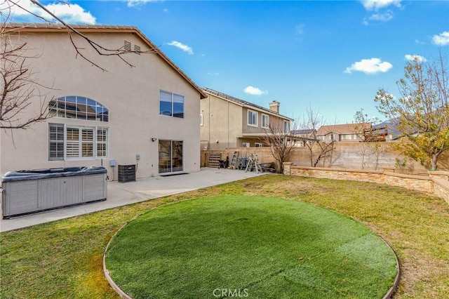 back of house featuring a yard, a patio area, and a hot tub