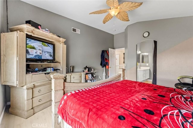 bedroom with ceiling fan, vaulted ceiling, and ensuite bath