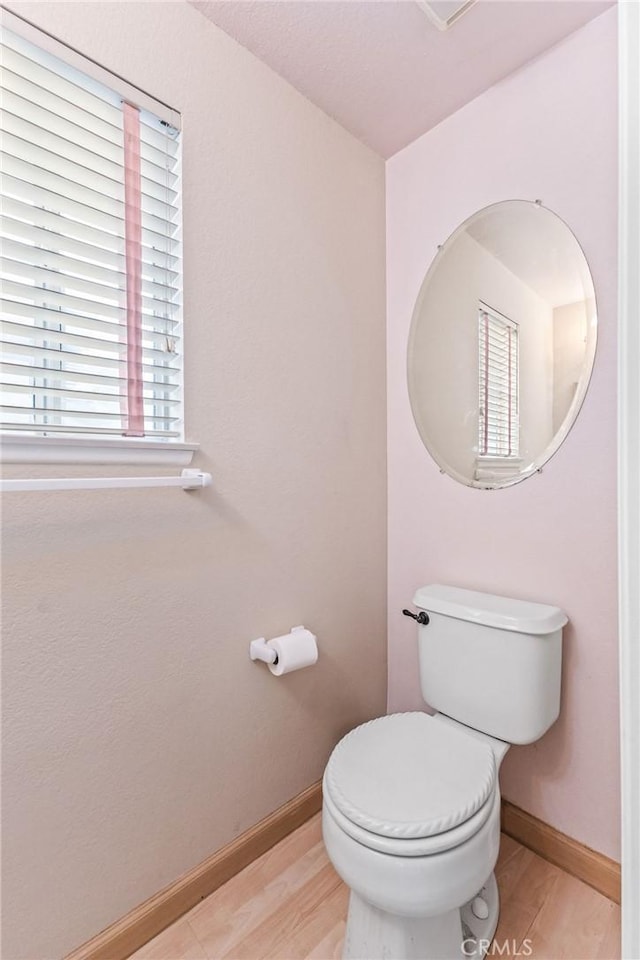 bathroom with a wealth of natural light, wood-type flooring, and toilet