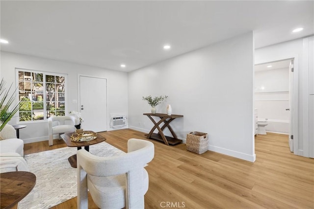 sitting room featuring a wall mounted air conditioner and light hardwood / wood-style floors