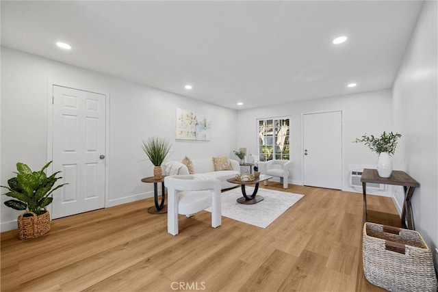 living room with a wall unit AC and light wood-type flooring