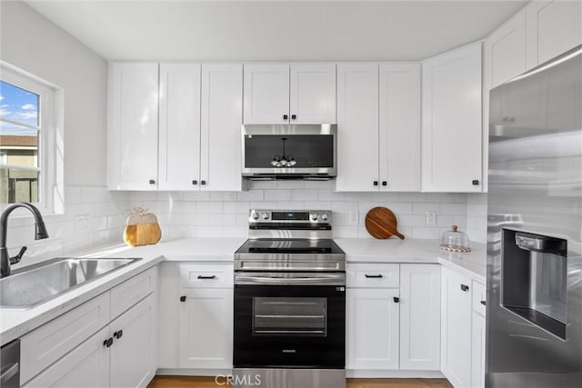 kitchen with white cabinetry, stainless steel appliances, sink, and decorative backsplash