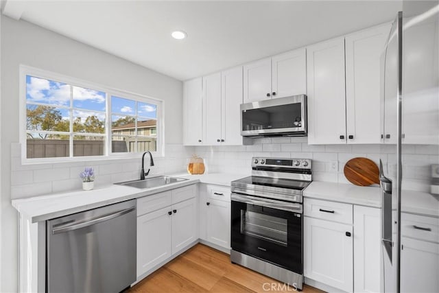 kitchen with tasteful backsplash, white cabinetry, appliances with stainless steel finishes, and sink