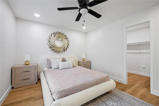 bedroom featuring a spacious closet, ceiling fan, and light wood-type flooring