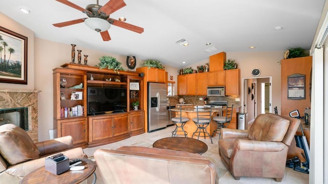 living room with a fireplace, vaulted ceiling, and ceiling fan