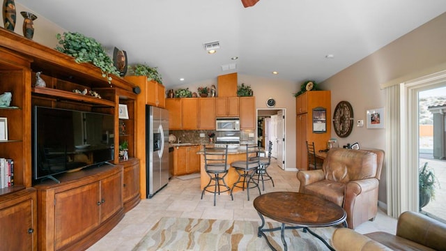 kitchen featuring appliances with stainless steel finishes, a kitchen breakfast bar, a center island, decorative backsplash, and vaulted ceiling