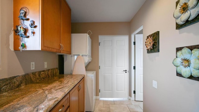 kitchen with stacked washer / drying machine, light tile patterned floors, and light stone countertops