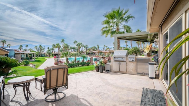 view of patio with a pool, an outdoor kitchen, and grilling area