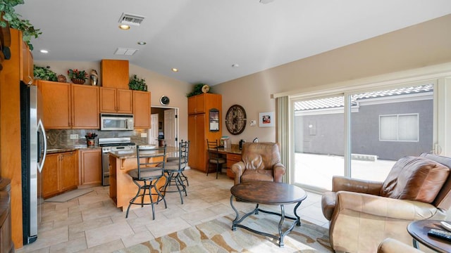 kitchen featuring a kitchen island, lofted ceiling, backsplash, a kitchen bar, and stainless steel appliances