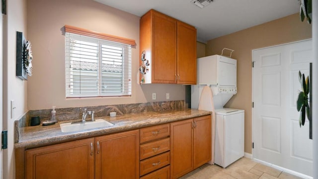 kitchen featuring stacked washer / drying machine, sink, and light tile patterned floors