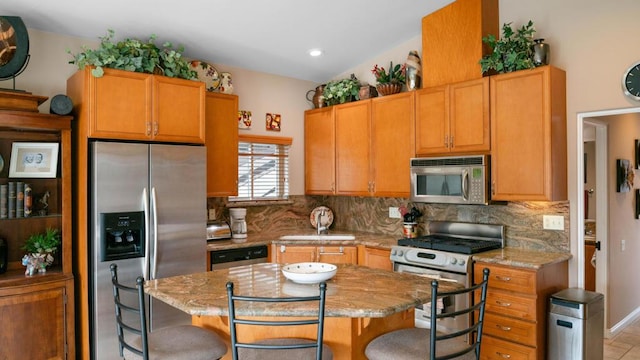 kitchen with light stone counters, appliances with stainless steel finishes, a breakfast bar, and a kitchen island