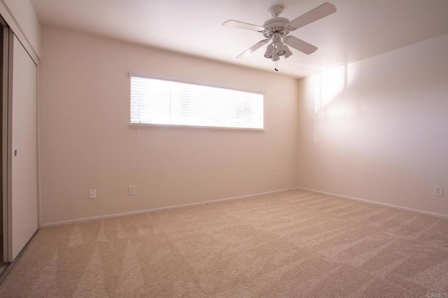 spare room with ceiling fan and light carpet