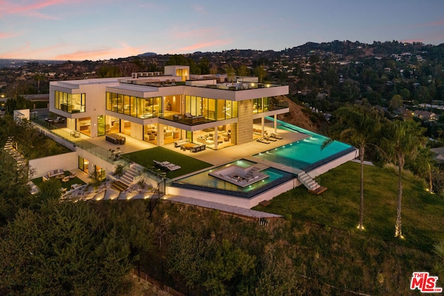 back house at dusk with a patio and an outdoor hangout area