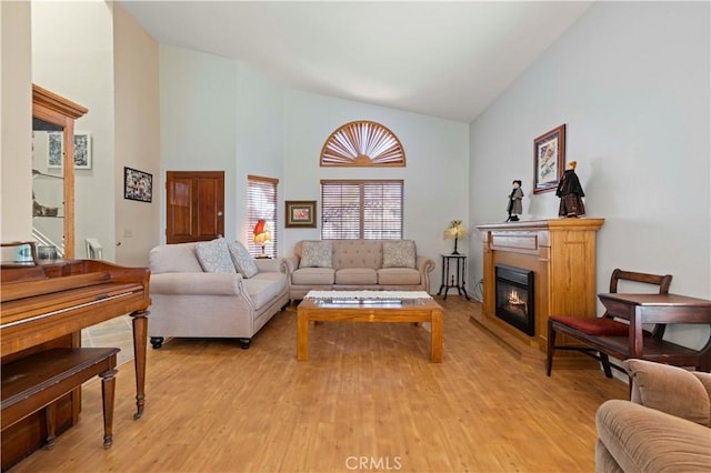 living room with high vaulted ceiling and light wood-type flooring