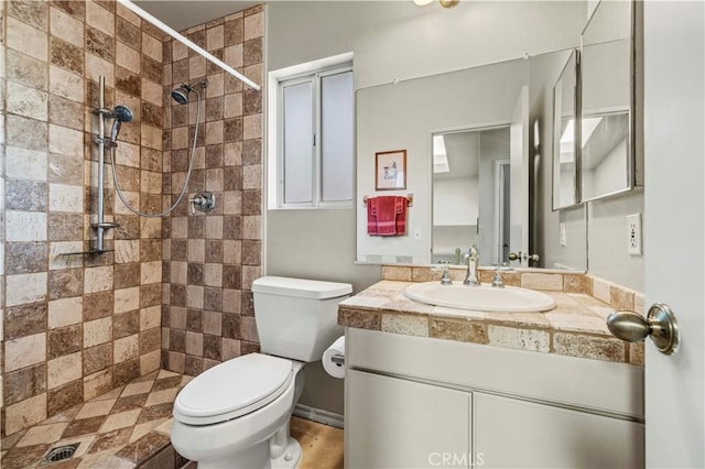 bathroom with vanity, toilet, and a tile shower