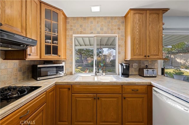 kitchen with tile countertops, tasteful backsplash, dishwasher, sink, and black gas stovetop