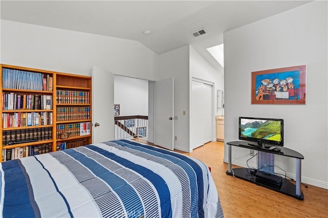 bedroom featuring lofted ceiling, connected bathroom, hardwood / wood-style flooring, and a closet