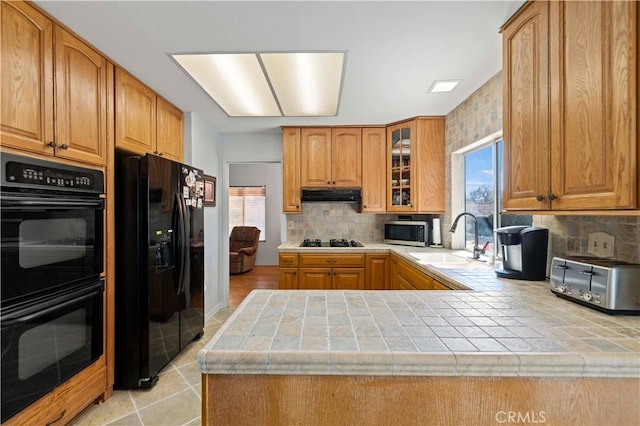 kitchen featuring tile countertops, tasteful backsplash, black appliances, sink, and kitchen peninsula