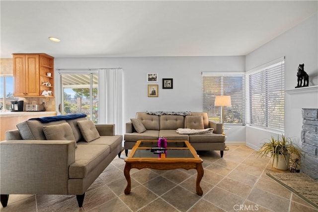 living room featuring a stone fireplace and a healthy amount of sunlight