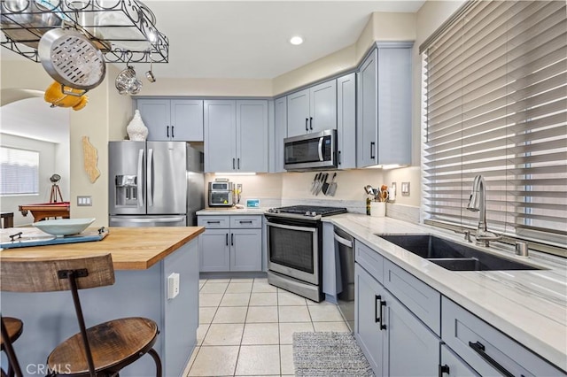 kitchen featuring stainless steel appliances, light stone countertops, sink, and light tile patterned floors