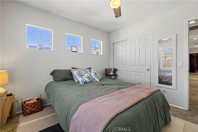 carpeted bedroom with ceiling fan and a closet